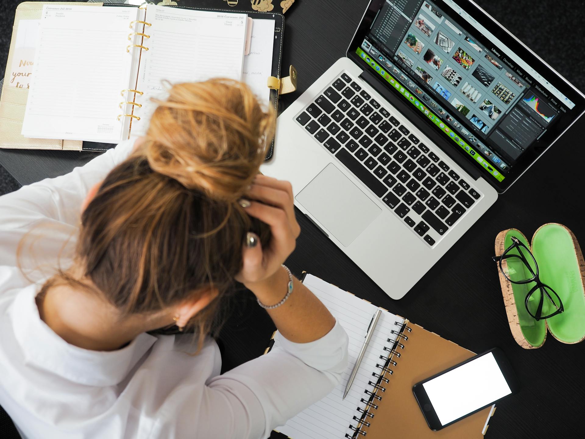 A woman sitting at her desk holding her head | Source: Pexels