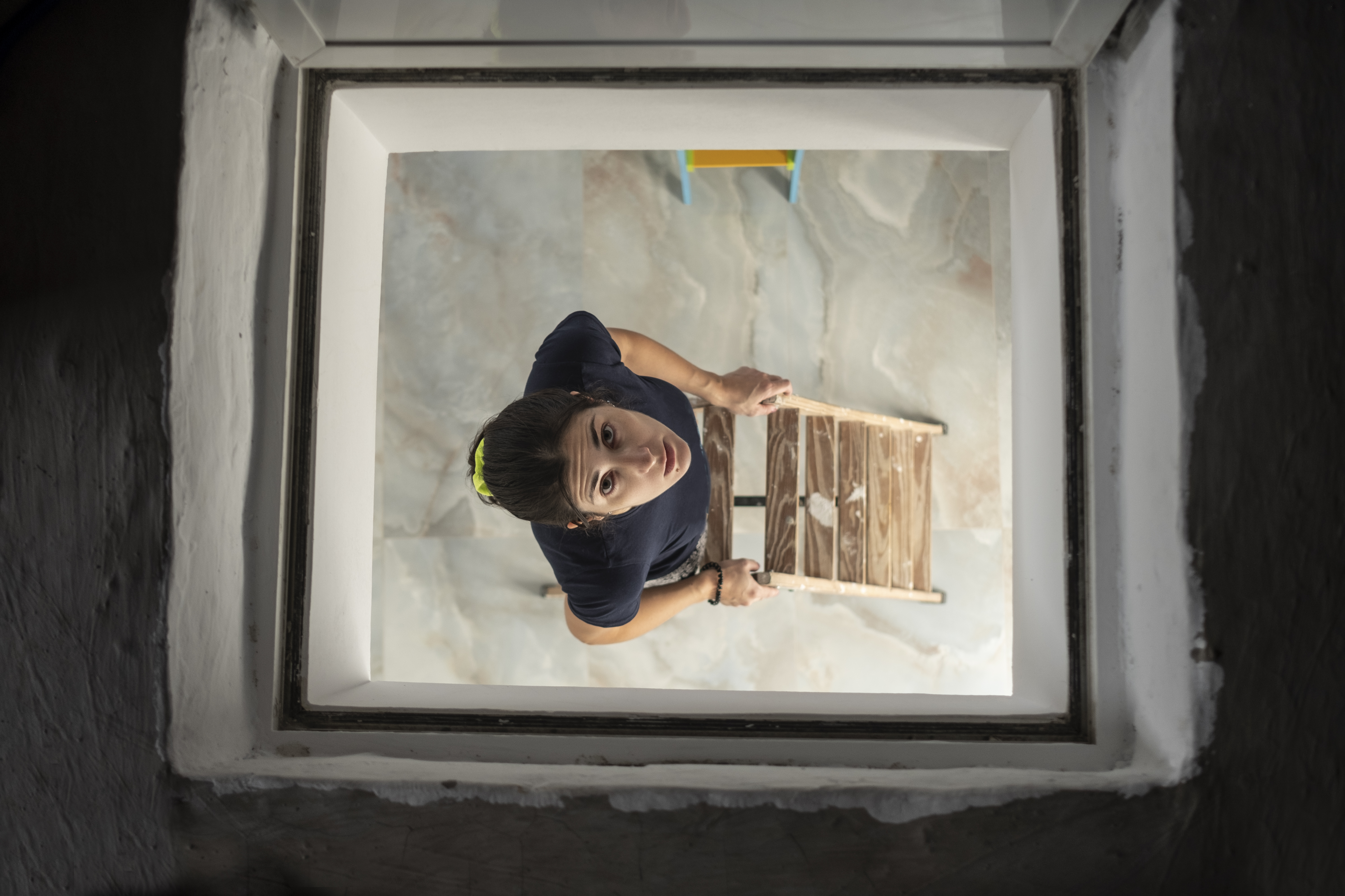 Woman peeks through the hatch of the stairs to the attic | Source: Getty Images