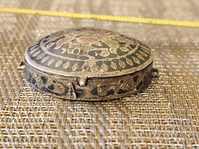 r/whatisthisthing - Small, 2.5 cm, silver case/box. I have had it at least 50 years and I have never known what it is. Possible hematite inlay on the lid and sides that looks worn. Hinge is just a brass loop. Clasp is broken. Small handle on each side. Long story as to how I got this thing.