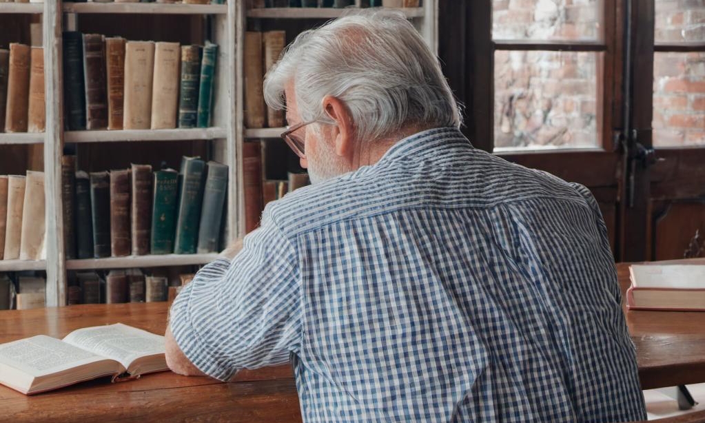 John sitting alone in his study, thinking of his late wife | Source: Midjourney