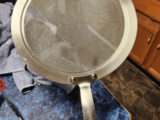 Found in a storage area with multiple pots and pans, a circular metal piece that includes a fine mesh screen.